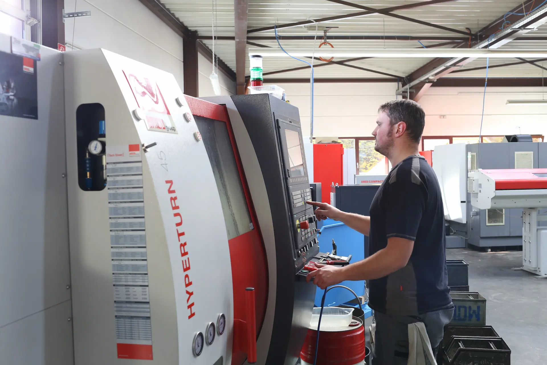 Facharbeiter programmiert EMCO Hyperturn 45 CNC-Drehmaschine für präzise Bauteilfertigung.