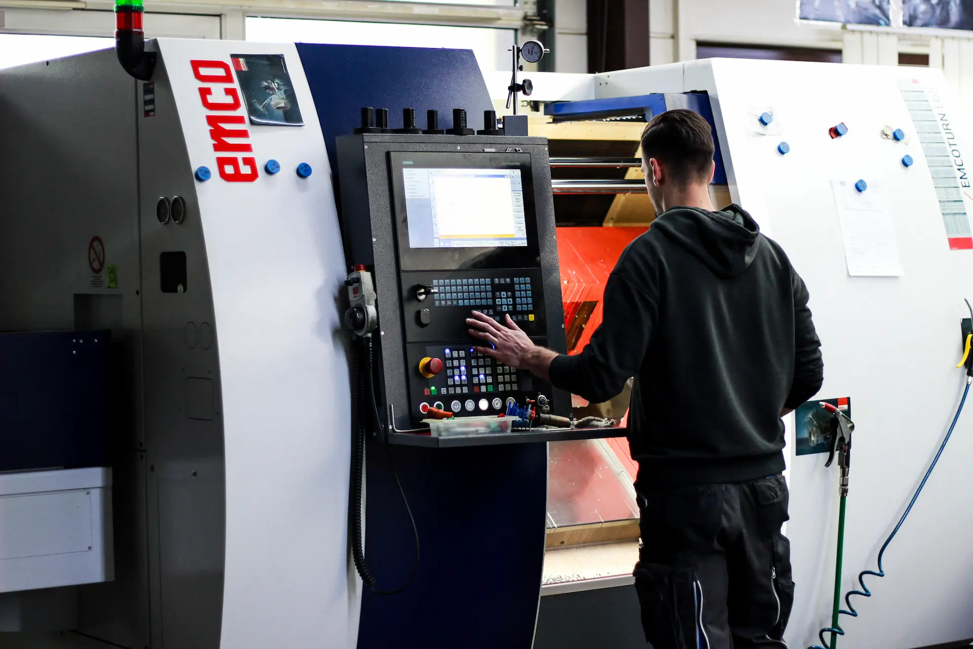 Mitarbeiter bedient CNC-Drehmaschine EMCOturn zur präzisen Bearbeitung technischer Bauteile.