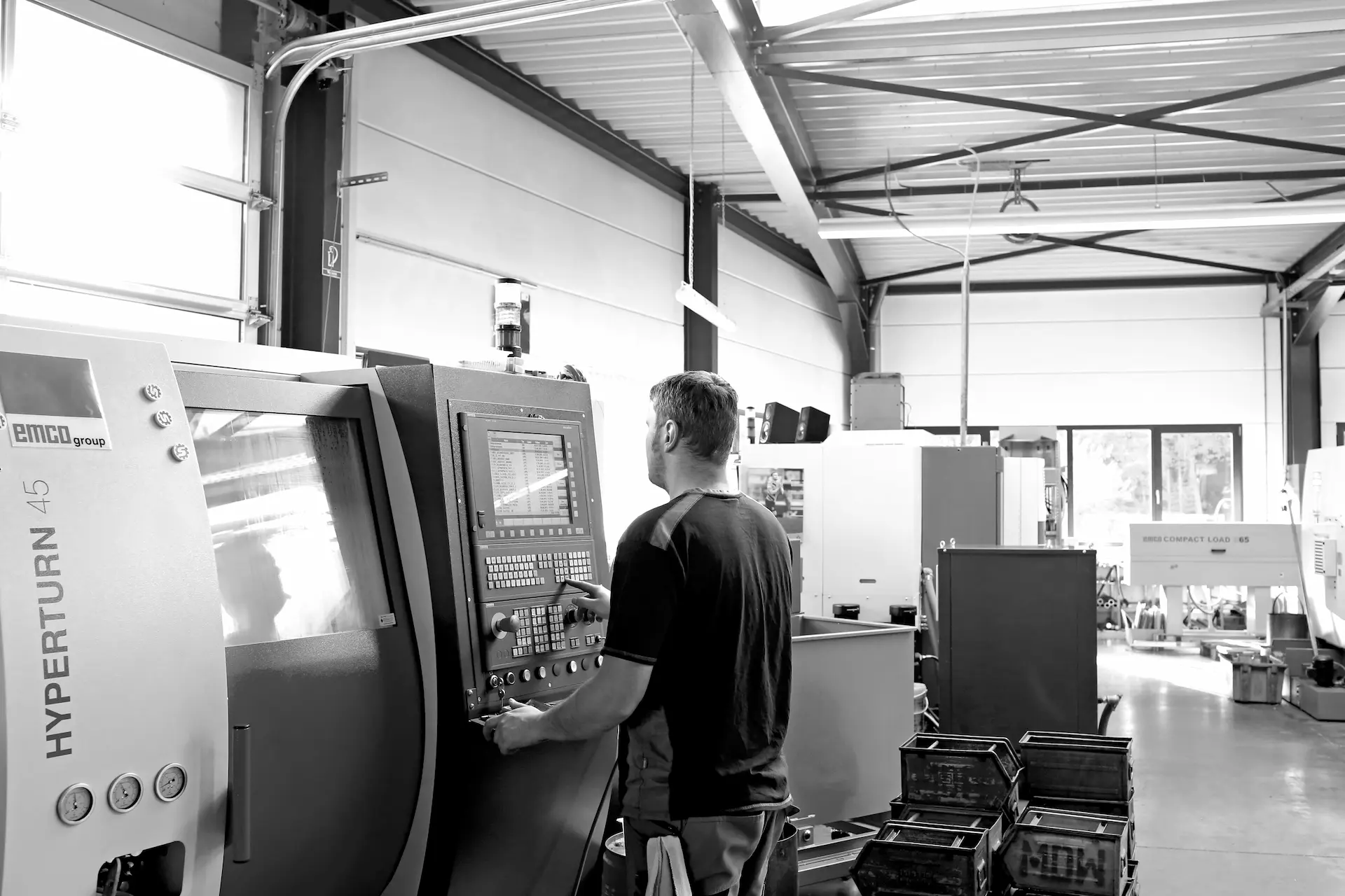 Mitarbeiter programmiert EMCO Hyperturn 45 CNC-Drehmaschine in der Fertigungshalle.