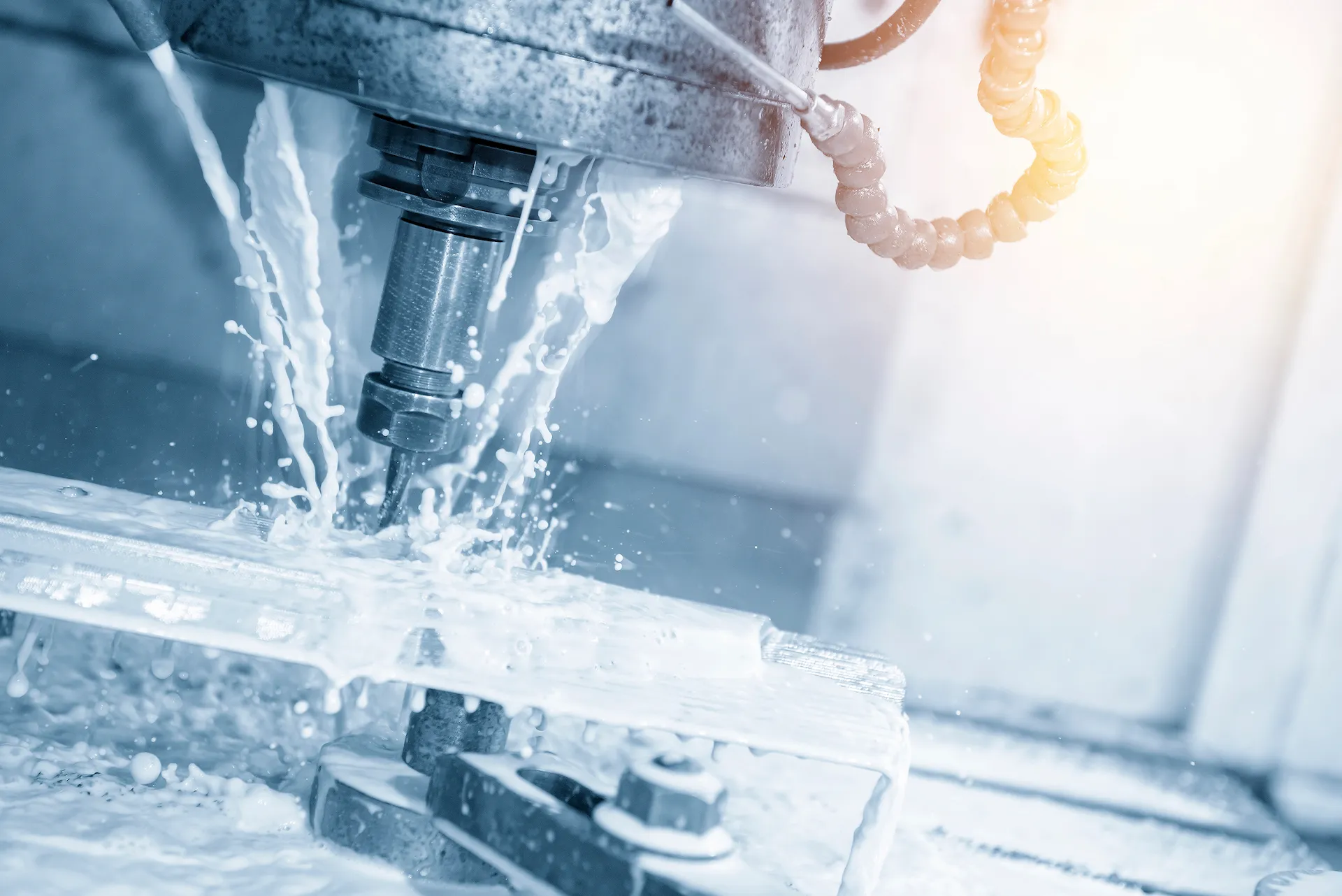 CNC-Fräsvorgang mit Kühlmittelzufuhr bei der Bearbeitung eines Metallteils.