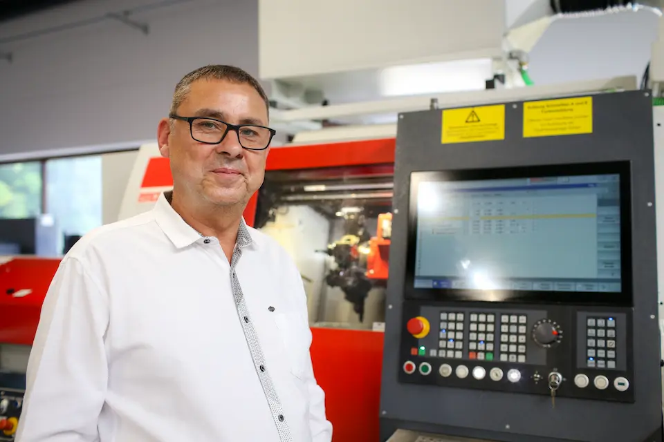 Jörg Weisheit, Geschäftsführer, vor CNC-Drehautomat in der Fertigungshalle.