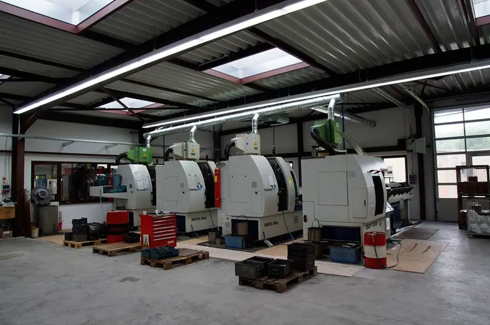 Blick in die Produktionshalle mit mehreren CNC-Drehmaschinen und Werkbänken.